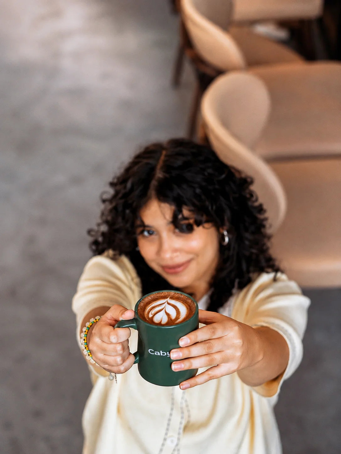 Customer holding a hot mocha coffee with latte art in a signature Caby & Byke mug inside the café.