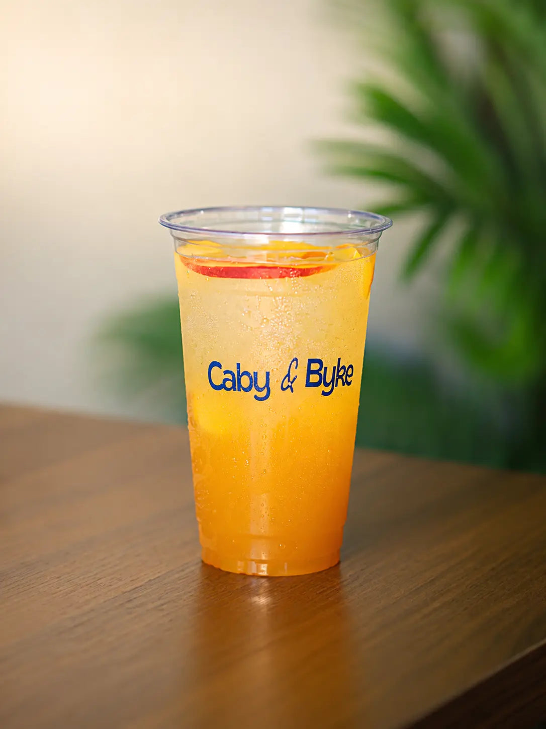 A cold Summer Fusion Chiller with ice and a fresh apple slice in a clear cup.