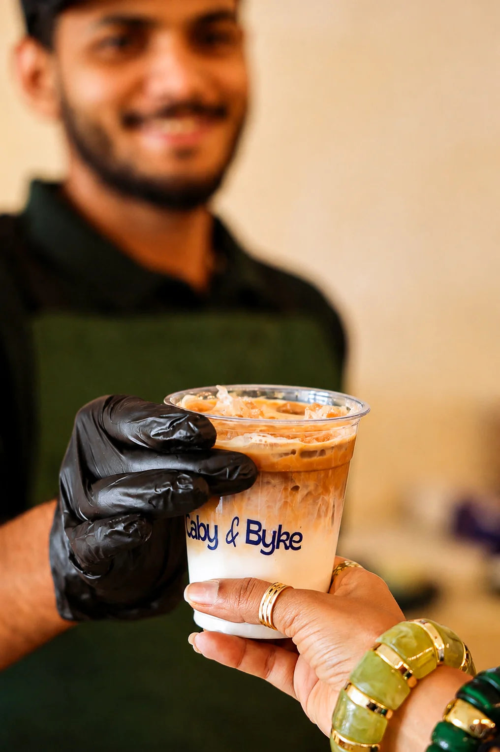 Fresh iced Spanish latte served to a customer in a takeaway cup with creamy milk and espresso