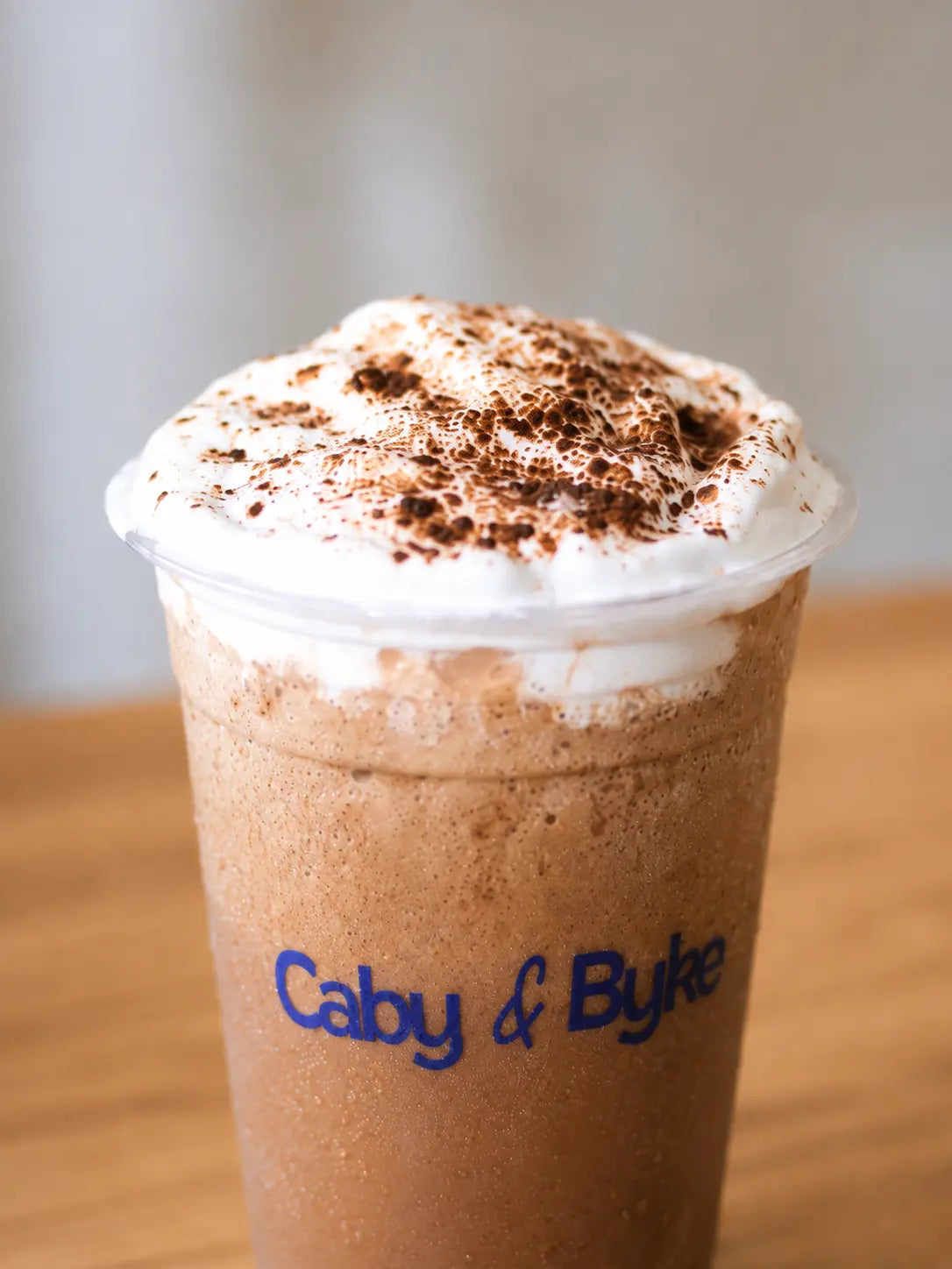 Close-up of a chilled Mocha Frappe with whipped cream and cocoa powder.